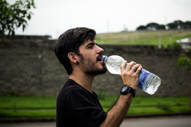 Importância da água para o corpo - Homem de camisa preta bebendo água